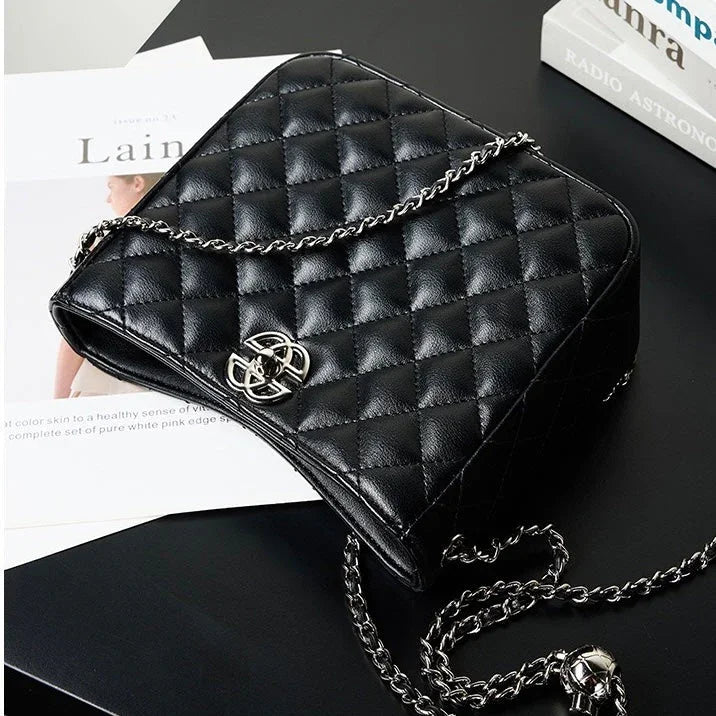 Black quilted leather crossbody bag with silver chain strap on black table