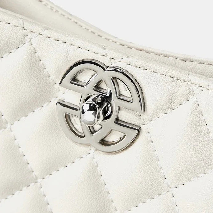 Close-up of quilted white leather handbag with silver metal turn-lock clasp