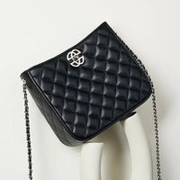Black quilted leather crossbody bag with silver chain strap and metal logo on display