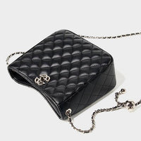Black quilted leather crossbody bag with gold chain strap and metallic logo on white background