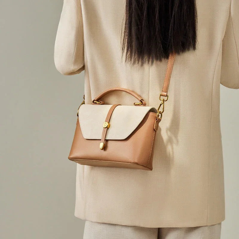 Woman in beige suit wearing a stylish tan leather crossbody handbag with gold hardware
