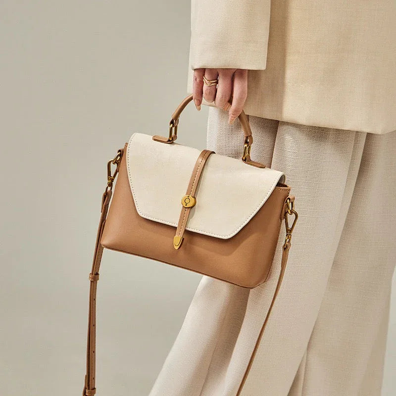 Woman in beige outfit holding a two-tone tan and cream leather handbag