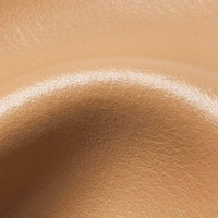 Close-up of smooth beige leather texture with curved contour for upholstery or accessories