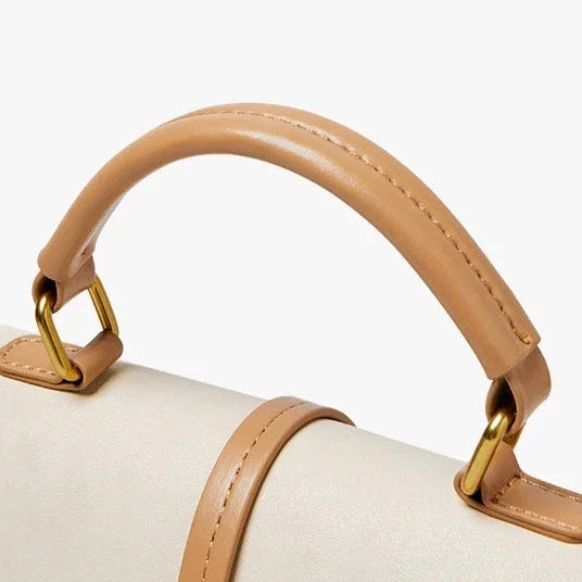 Beige leather handbag handle with gold hardware on a white background