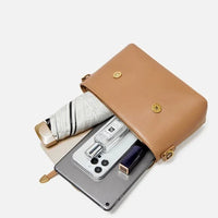 Tan leather crossbody bag with umbrella, perfume, smartphone, tablet, and lipstick inside