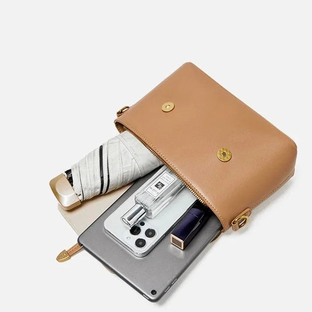 Tan leather crossbody bag with umbrella, perfume, smartphone, tablet, and lipstick inside