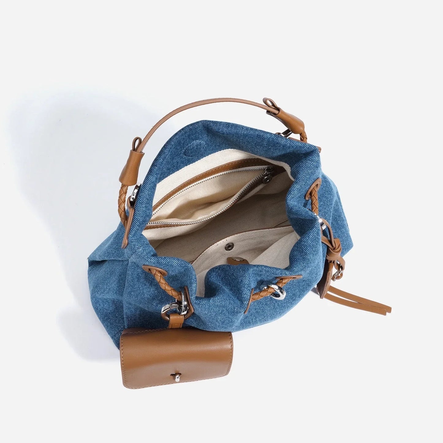 Blue denim bucket bag with tan leather handle and beige interior pockets