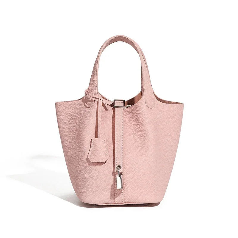 Blush pink leather tote bag with textured finish and silver lock accent on white background