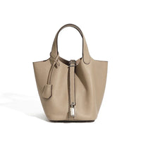 Taupe leather tote bag with pebbled texture and silver lock accent on white background