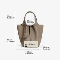 Taupe leather bucket bag with handle, size measurements, and phone for scale