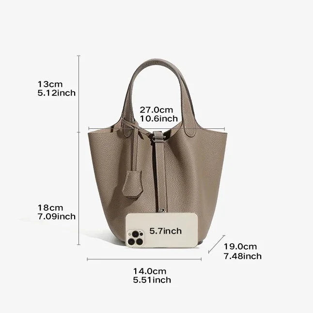 Taupe leather bucket bag with handle, size measurements, and phone for scale