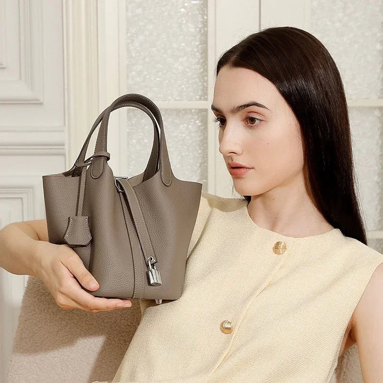 Woman holding taupe leather handbag indoors, fashion accessory, modern minimalist style