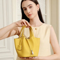 Woman in cream dress holding yellow leather handbag in bright room