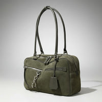 Olive green suede handbag with double handles, front zip pocket, and silver hardware