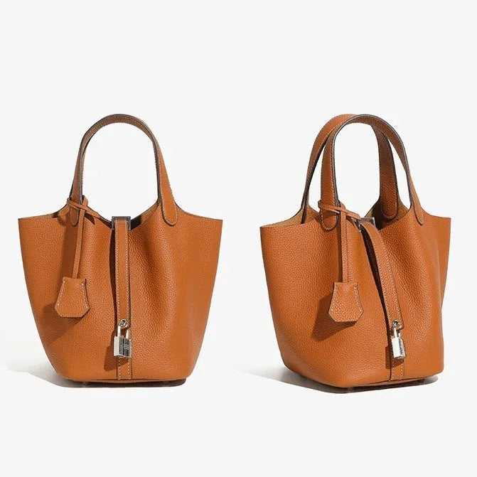 Two brown leather bucket handbags with top handles and silver padlock detail on white background