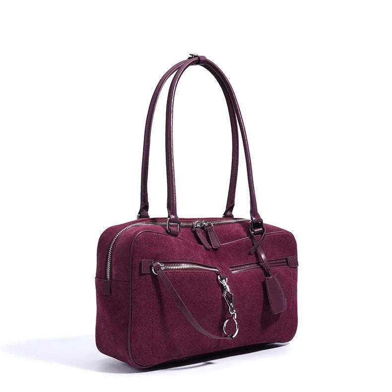 Burgundy suede leather handbag with long straps and front zip pocket on white background