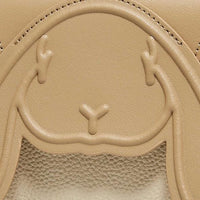 Embossed bunny face on textured tan leather bag close-up