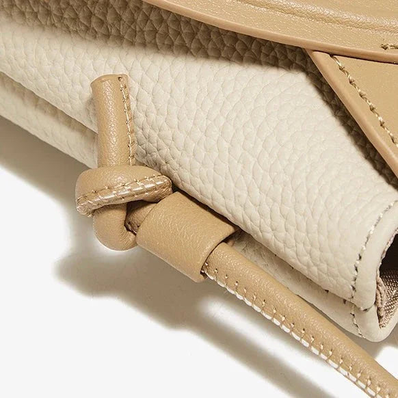 Close-up of beige pebbled leather handbag with knotted detail and textured finish