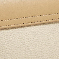Close-up of beige and cream textured leather with visible stitching detail