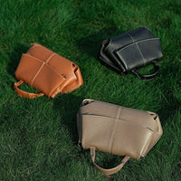 Three leather handbags in tan, black, and beige on green grass outdoor setting