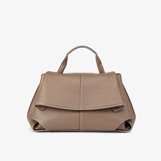 Taupe leather handbag with top handle and front flap on white background