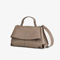 Taupe leather handbag with top handle and shoulder strap on white background