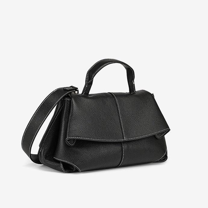 Black leather handbag with top handle and shoulder strap on white background
