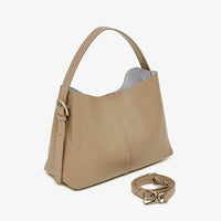 Beige leather shoulder bag with gold buckle and detachable strap on white background