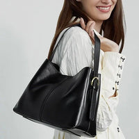 Woman in white blouse carrying a black leather shoulder bag fashion accessory