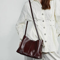 Woman wearing white blouse with brown leather shoulder bag