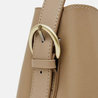 Close-up beige leather handbag with gold buckle on white background