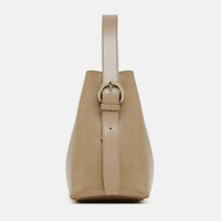 Side view of beige leather handbag with strap and gold buckle on white background