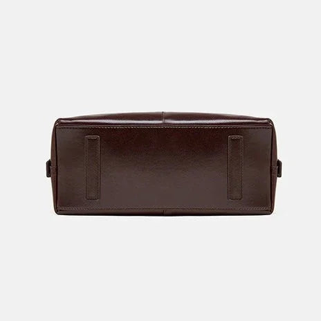 Bottom view of a dark brown leather bag on a white background