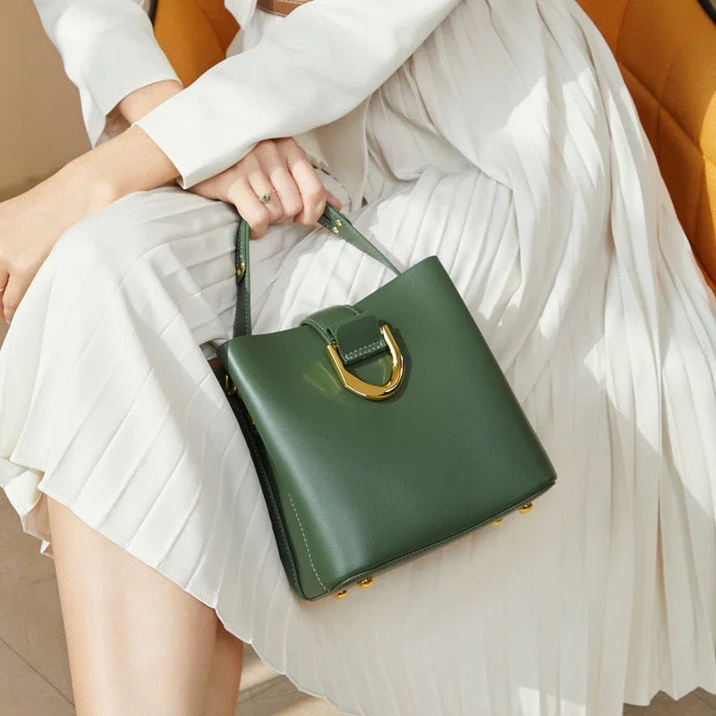 Woman in white dress holding green leather handbag with gold hardware