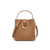 Tan leather bucket bag with gold buckle and adjustable shoulder strap on white background