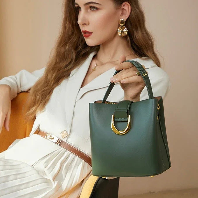 Woman in white outfit holding green leather handbag with gold hardware, fashion accessories