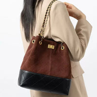Woman in beige blazer with brown and black quilted bucket bag, gold chain strap