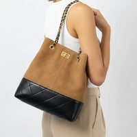 Woman wearing a tan and black quilted bucket bag with gold chain strap