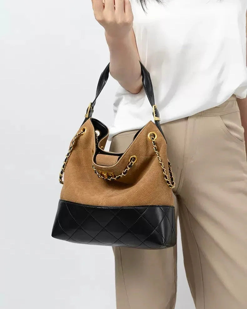 Woman holding a brown suede and black leather chain shoulder bag