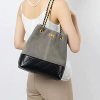 Woman wearing a gray and black quilted bucket bag with gold chain straps