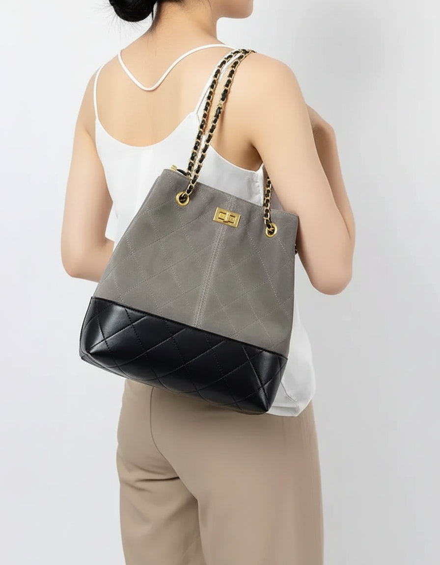 Woman wearing a gray and black quilted bucket bag with gold chain straps