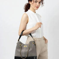 Woman holding gray and black quilted leather handbag with gold chain handle