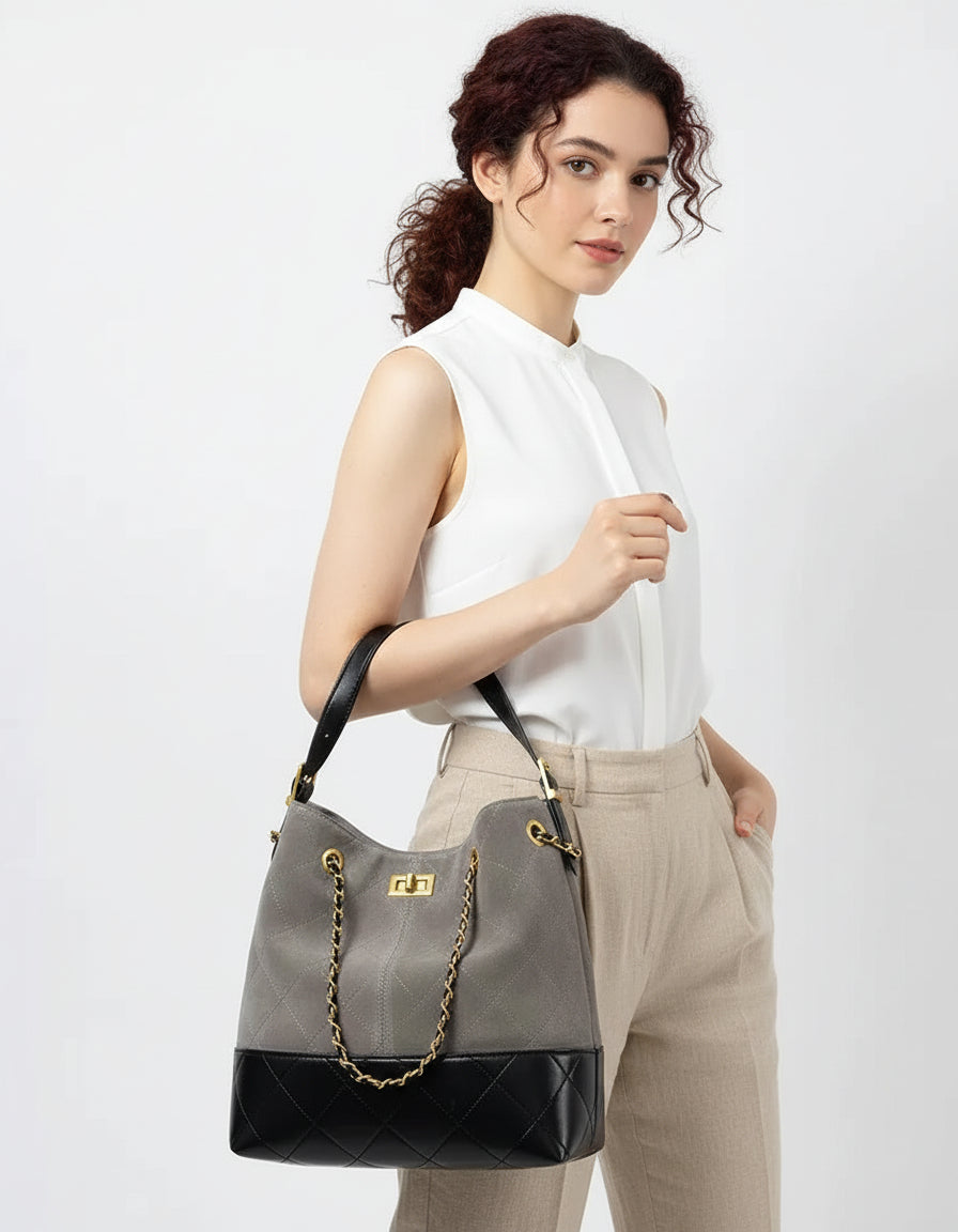 Woman holding gray and black quilted leather handbag with gold chain handle
