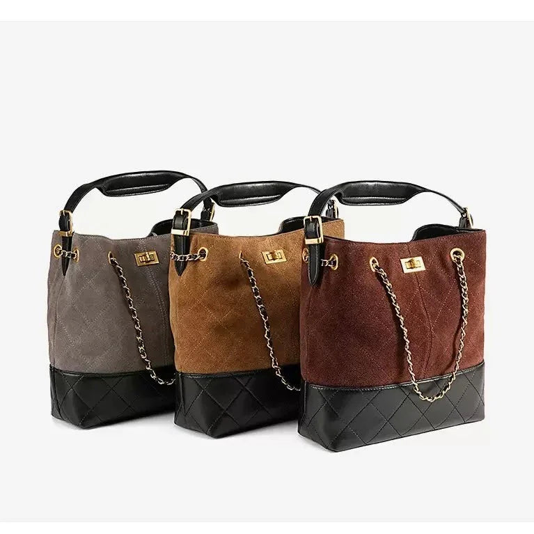 Trio of suede and leather bucket handbags with gold chain straps in gray, brown, and burgundy