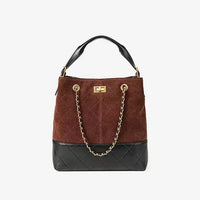 Brown and black suede and leather bucket bag with gold chain and top handle on white background