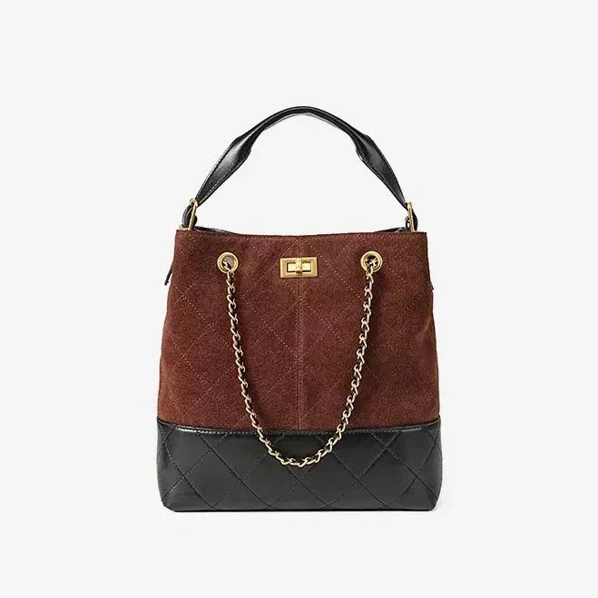 Brown and black suede and leather bucket bag with gold chain and top handle on white background