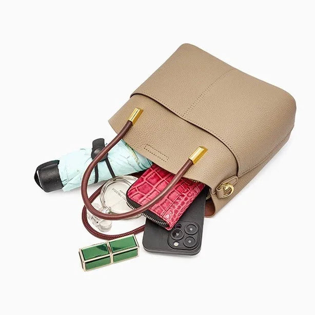 Beige leather handbag with wallet, phone, umbrella, and accessories spilling out