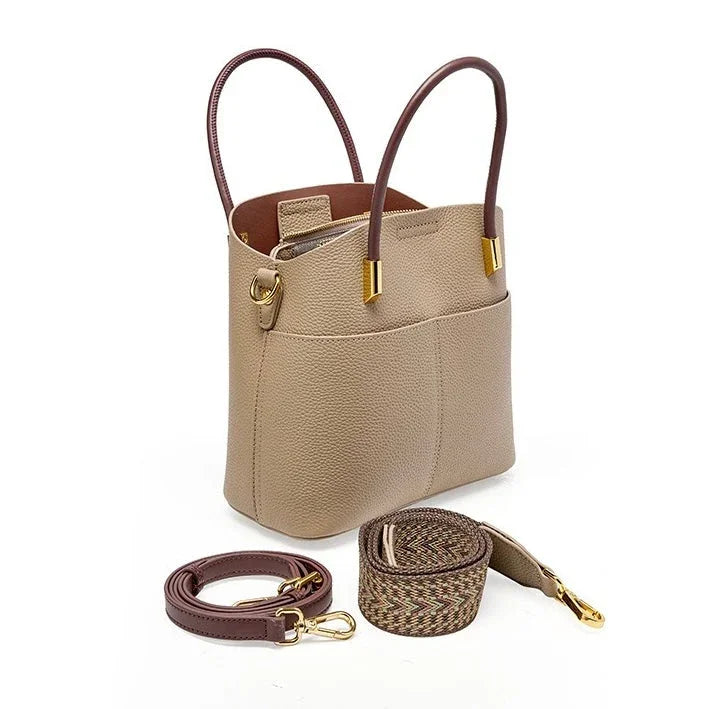 Taupe leather tote bag with brown handles, gold hardware, and detachable straps on white background.