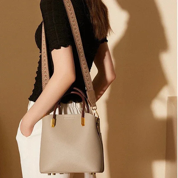 Woman wearing black top, white pants, and carrying a beige leather shoulder bag