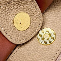 Close-up of a beige and brown leather handbag magnetic snap closure with gold hardware